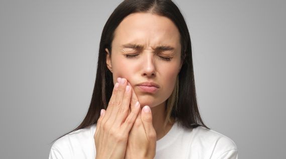 Emergency Dental Care - Woman with tooth pain touching the left cheek