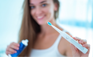 woman holding electronic toothbrush