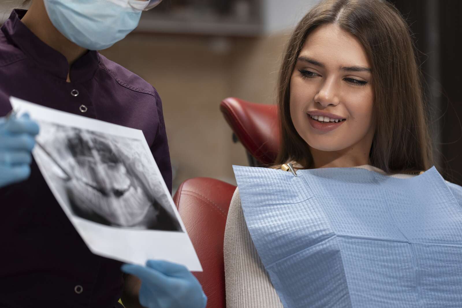 Dentist showing an X-ray to a patient in a dental chair.